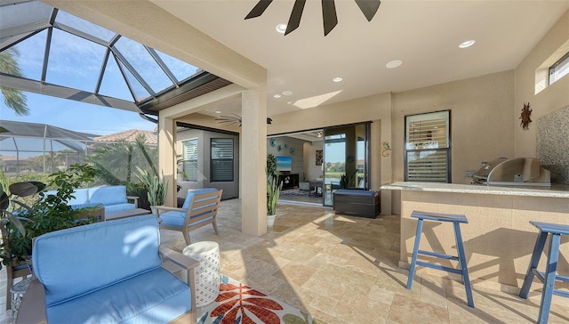 view of patio featuring exterior bar, glass enclosure, ceiling fan, and exterior kitchen