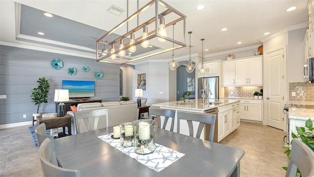 dining space with a tray ceiling, sink, and ornamental molding