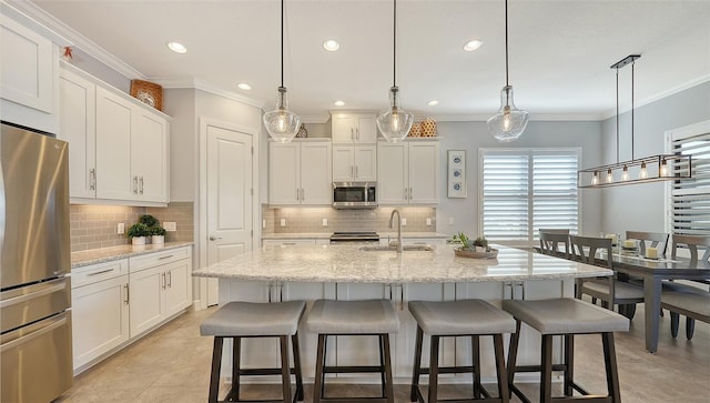 kitchen with sink, stainless steel appliances, hanging light fixtures, and an island with sink