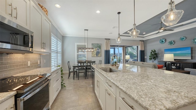 kitchen featuring white cabinets, ornamental molding, an island with sink, and appliances with stainless steel finishes