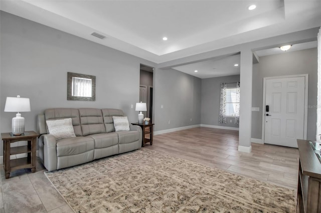 living room featuring a raised ceiling and light hardwood / wood-style flooring