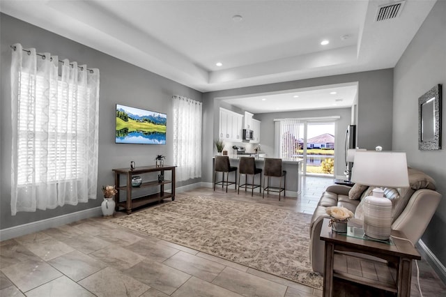 tiled living room featuring a raised ceiling