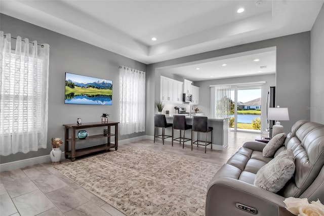 living room with a raised ceiling and sink