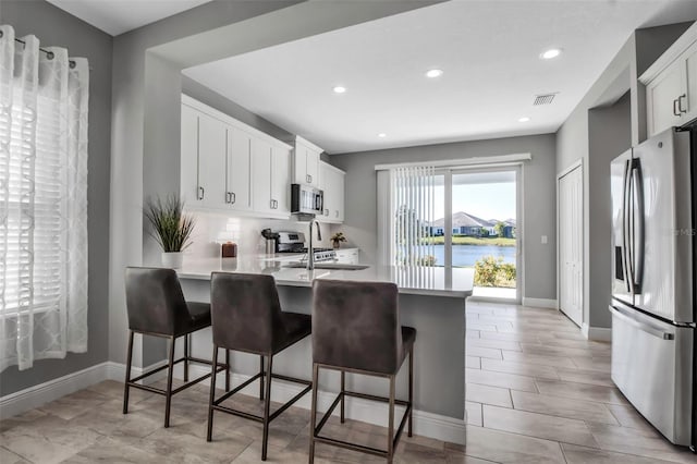 kitchen with white cabinets, a kitchen bar, stainless steel appliances, and a water view