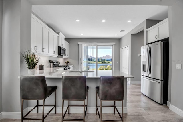 kitchen featuring white cabinets, a kitchen breakfast bar, sink, and appliances with stainless steel finishes