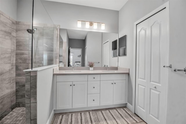 bathroom with a tile shower and vanity