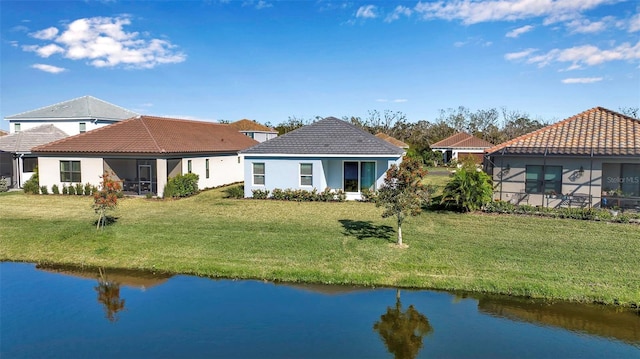 back of house featuring a lawn and a water view