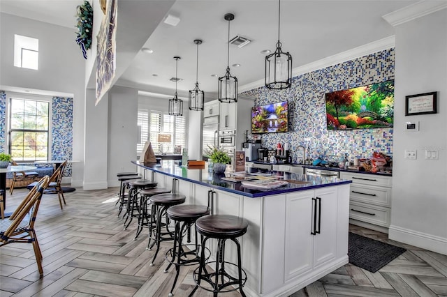 kitchen featuring white cabinets, decorative light fixtures, a healthy amount of sunlight, and light parquet floors