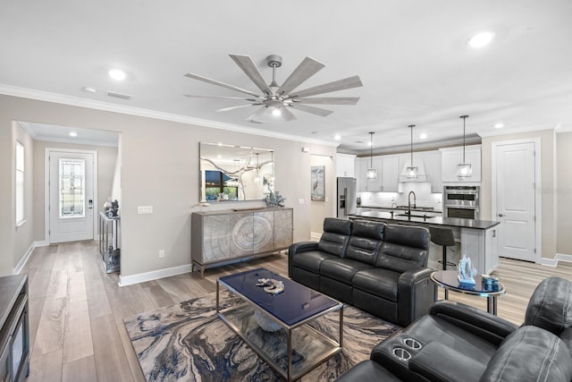 living room featuring ceiling fan, ornamental molding, light hardwood / wood-style floors, and sink