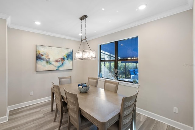 dining space featuring wood-type flooring, an inviting chandelier, and crown molding