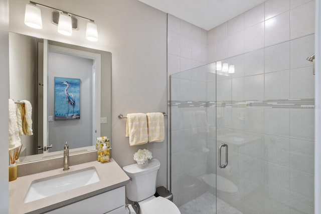 bathroom featuring toilet, a shower with shower door, and vanity