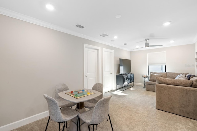 carpeted dining room featuring ceiling fan and ornamental molding