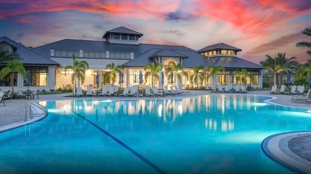 pool at dusk featuring a patio