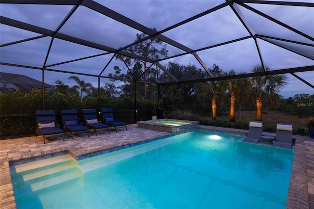 pool at dusk featuring a lanai, an in ground hot tub, and a patio