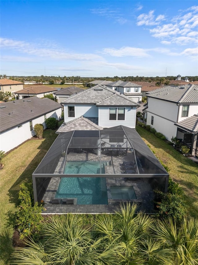 exterior space featuring a yard, glass enclosure, and an in ground hot tub