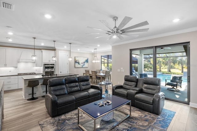 living room with a wealth of natural light, crown molding, and light hardwood / wood-style floors