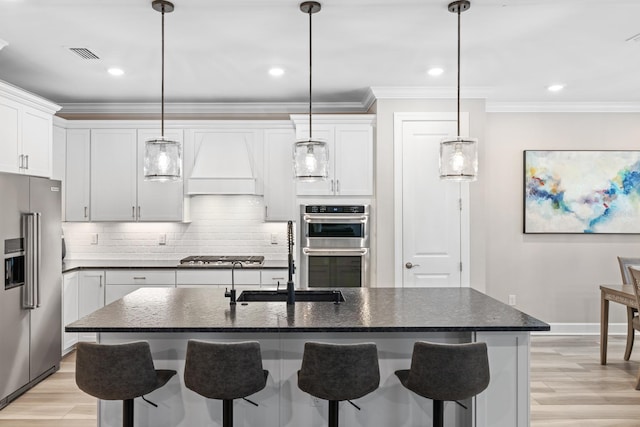 kitchen with white cabinetry, stainless steel appliances, a kitchen island with sink, and custom exhaust hood