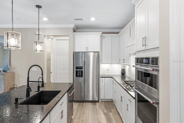 kitchen with decorative light fixtures, dark stone countertops, stainless steel appliances, ornamental molding, and white cabinets