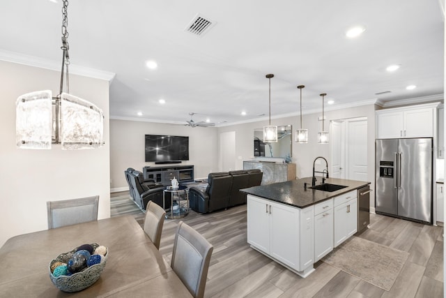 kitchen with pendant lighting, a center island with sink, sink, appliances with stainless steel finishes, and white cabinets