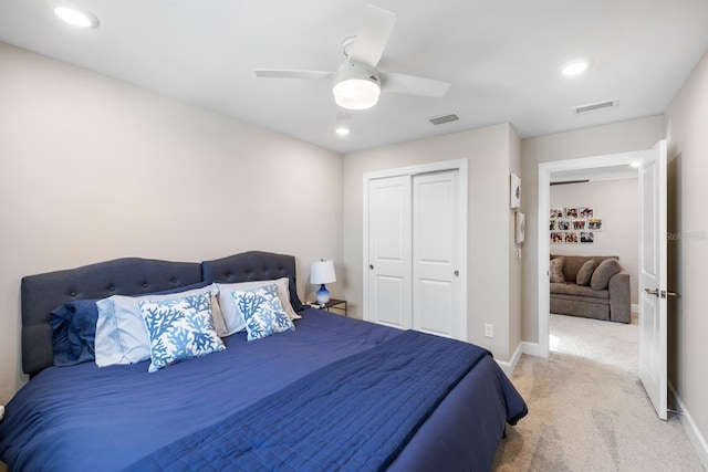 bedroom with ceiling fan, light colored carpet, and a closet