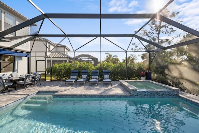 view of swimming pool with an in ground hot tub, glass enclosure, and a patio