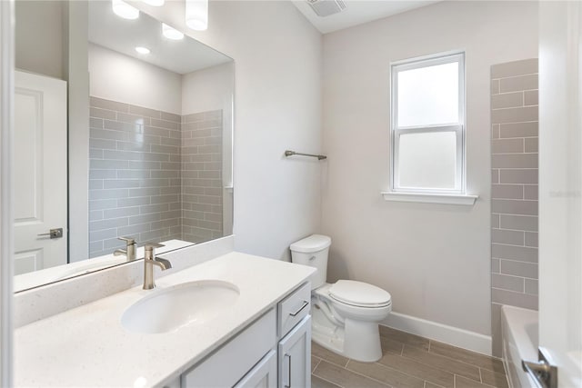 full bathroom with tiled shower / bath, vanity, and toilet