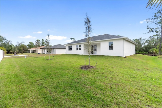 rear view of property featuring a lawn