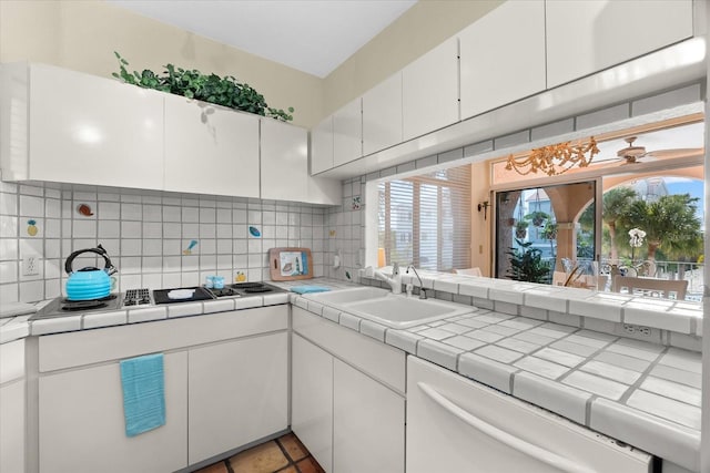 kitchen with tile countertops, white cabinetry, sink, decorative backsplash, and white dishwasher