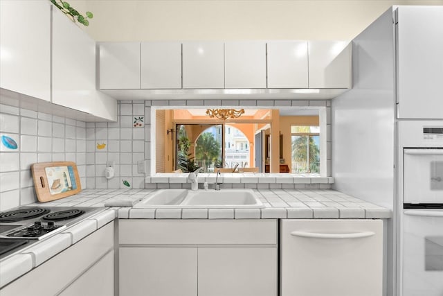 kitchen with decorative backsplash, tile countertops, and white cabinets