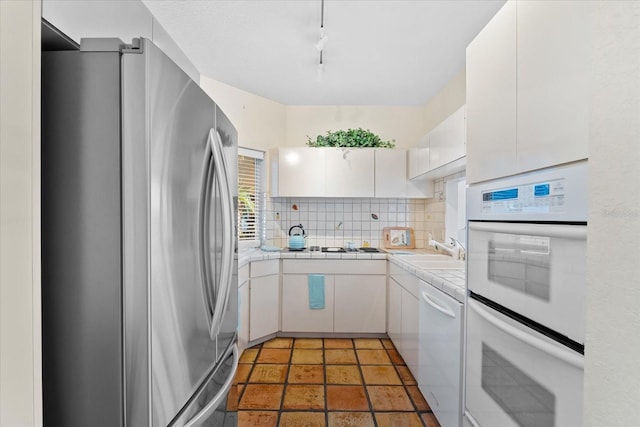 kitchen with sink, tile countertops, white appliances, decorative backsplash, and white cabinets