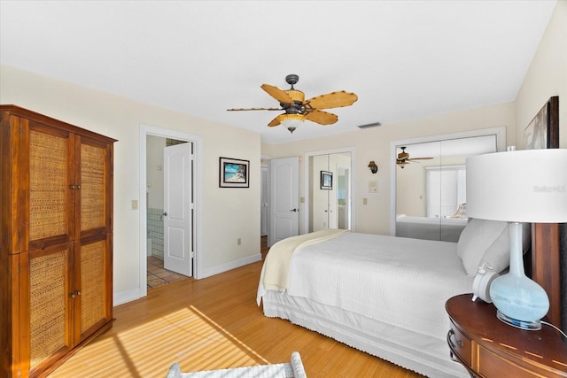 bedroom with multiple closets, hardwood / wood-style floors, and ceiling fan