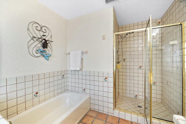 bathroom featuring plus walk in shower, tile walls, and tile patterned floors