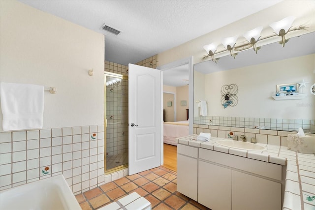 bathroom with tile patterned floors, plus walk in shower, a textured ceiling, and vanity