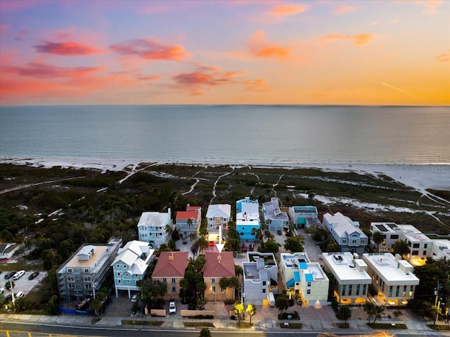 aerial view at dusk with a view of the beach and a water view