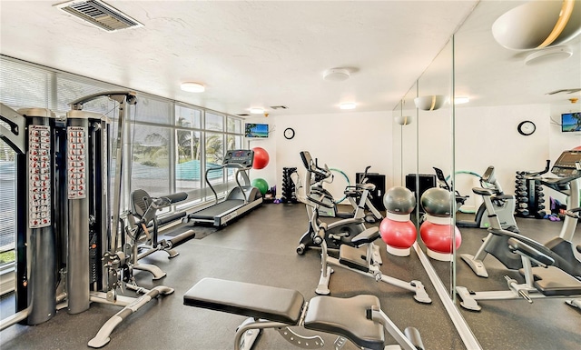 workout area featuring a wall of windows and a textured ceiling