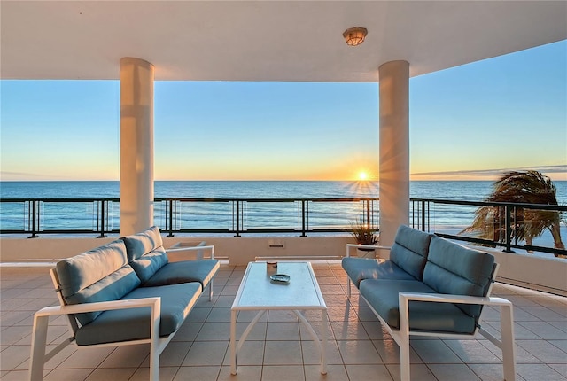 patio terrace at dusk featuring a water view, a balcony, and an outdoor hangout area