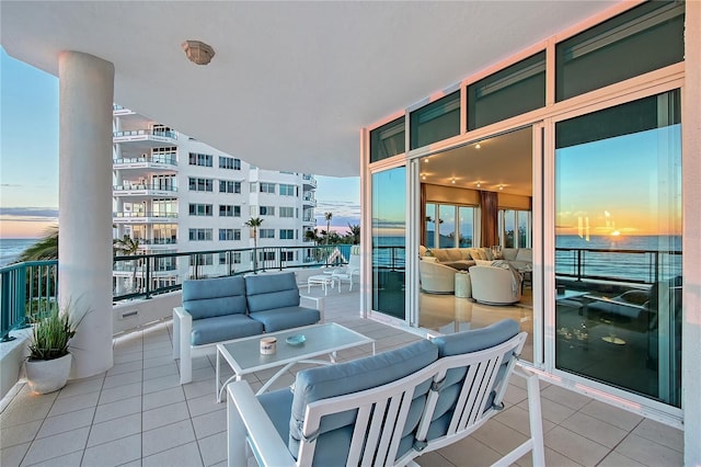 balcony at dusk featuring a water view and an outdoor living space