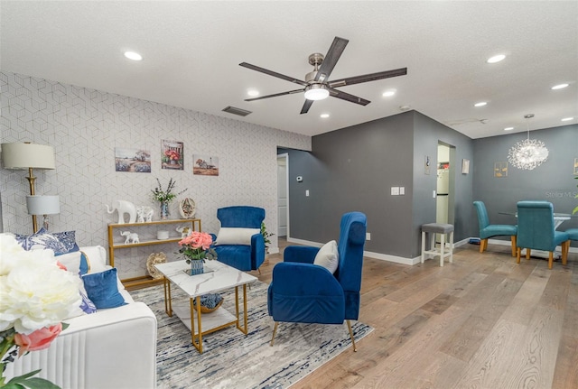 living room featuring hardwood / wood-style flooring, ceiling fan, and a textured ceiling