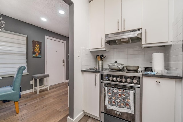 kitchen featuring white cabinets, stainless steel range, light hardwood / wood-style floors, and backsplash