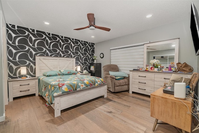 bedroom with ceiling fan, a textured ceiling, and light wood-type flooring