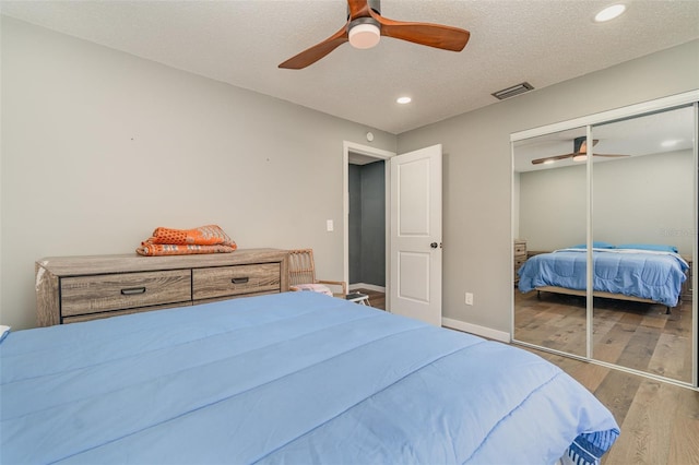 bedroom featuring hardwood / wood-style flooring, ceiling fan, a textured ceiling, and a closet