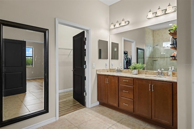 bathroom featuring tile patterned flooring, a tile shower, and vanity