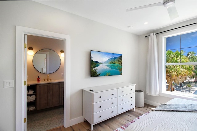 bedroom with ensuite bathroom, ceiling fan, light wood-type flooring, and sink