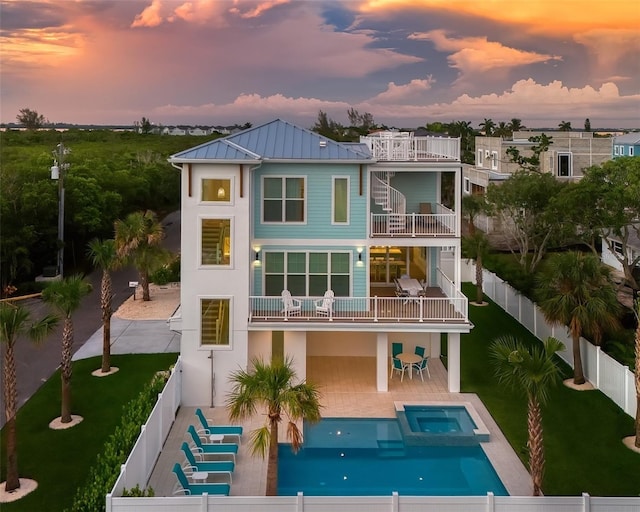 back house at dusk with a fenced in pool, a patio area, and a balcony