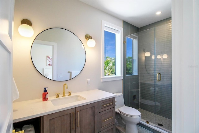 bathroom featuring a shower with door, vanity, and toilet