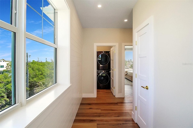 hall with stacked washer / drying machine and dark hardwood / wood-style flooring