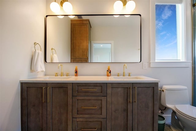 bathroom with an inviting chandelier, vanity, and toilet