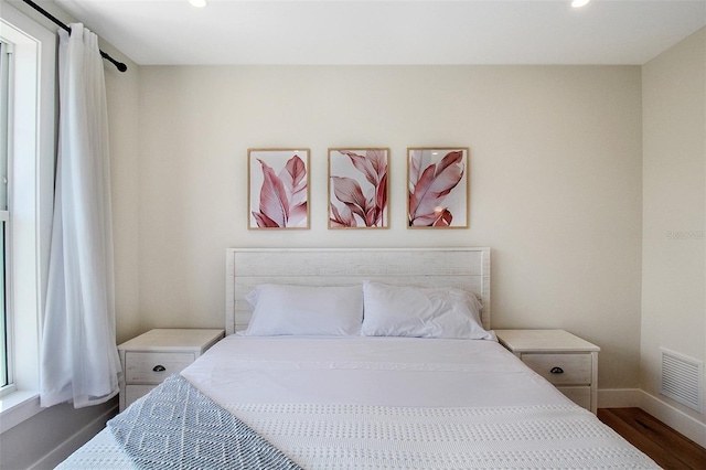 bedroom with multiple windows and dark hardwood / wood-style floors