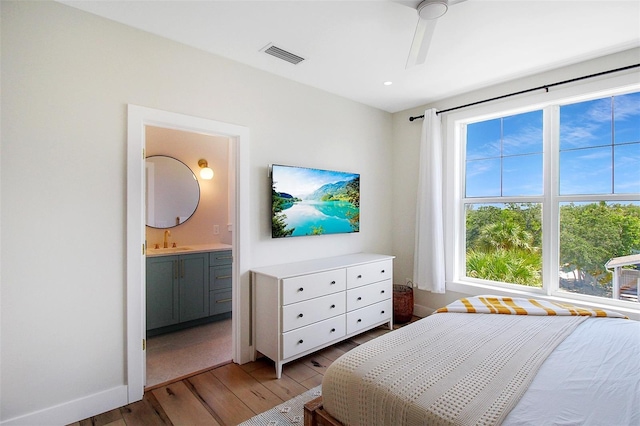 bedroom featuring sink, ensuite bath, and light hardwood / wood-style flooring