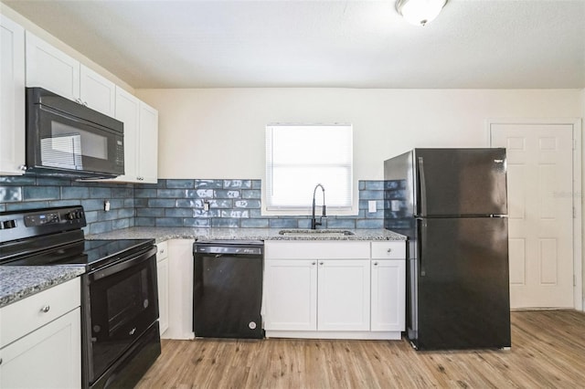 kitchen with black appliances, white cabinetry, sink, and light hardwood / wood-style flooring